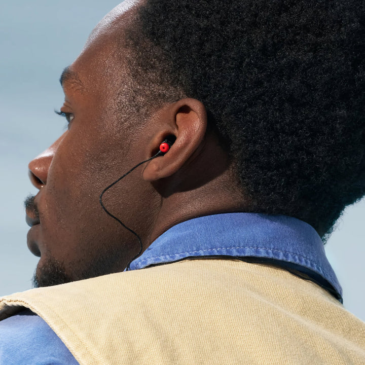 Man wearing Alpine WorkSafe earplugs with black cord, showing secure fit and in-use application for work environments