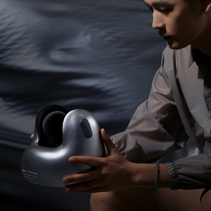 Man holding EVERYTHINK E2-X metallic silver travel neck pillow in a dark modern setting