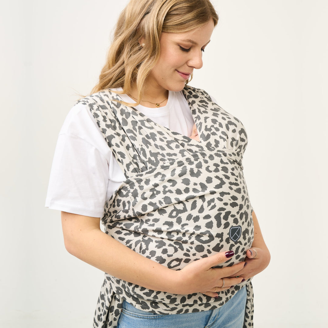 Koala Cuddle Band 2 leopard print wrap with baby held close on front, worn by smiling woman