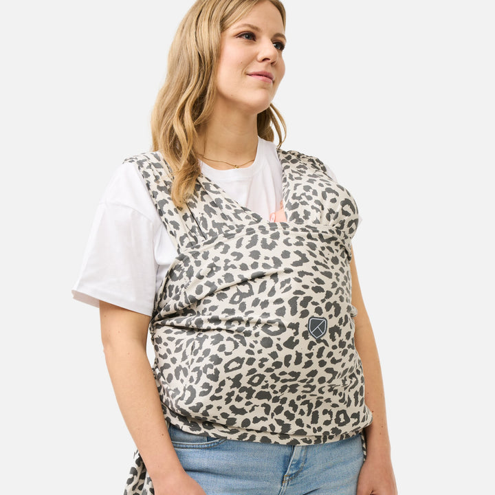 Woman wearing Koala Babycare Cuddle Band 2 baby wrap in leopard print, holding baby close on front.