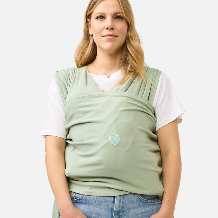 Woman wearing Koala Babycare Koala Cuddle Band 2 baby carrier in sage green, front view
