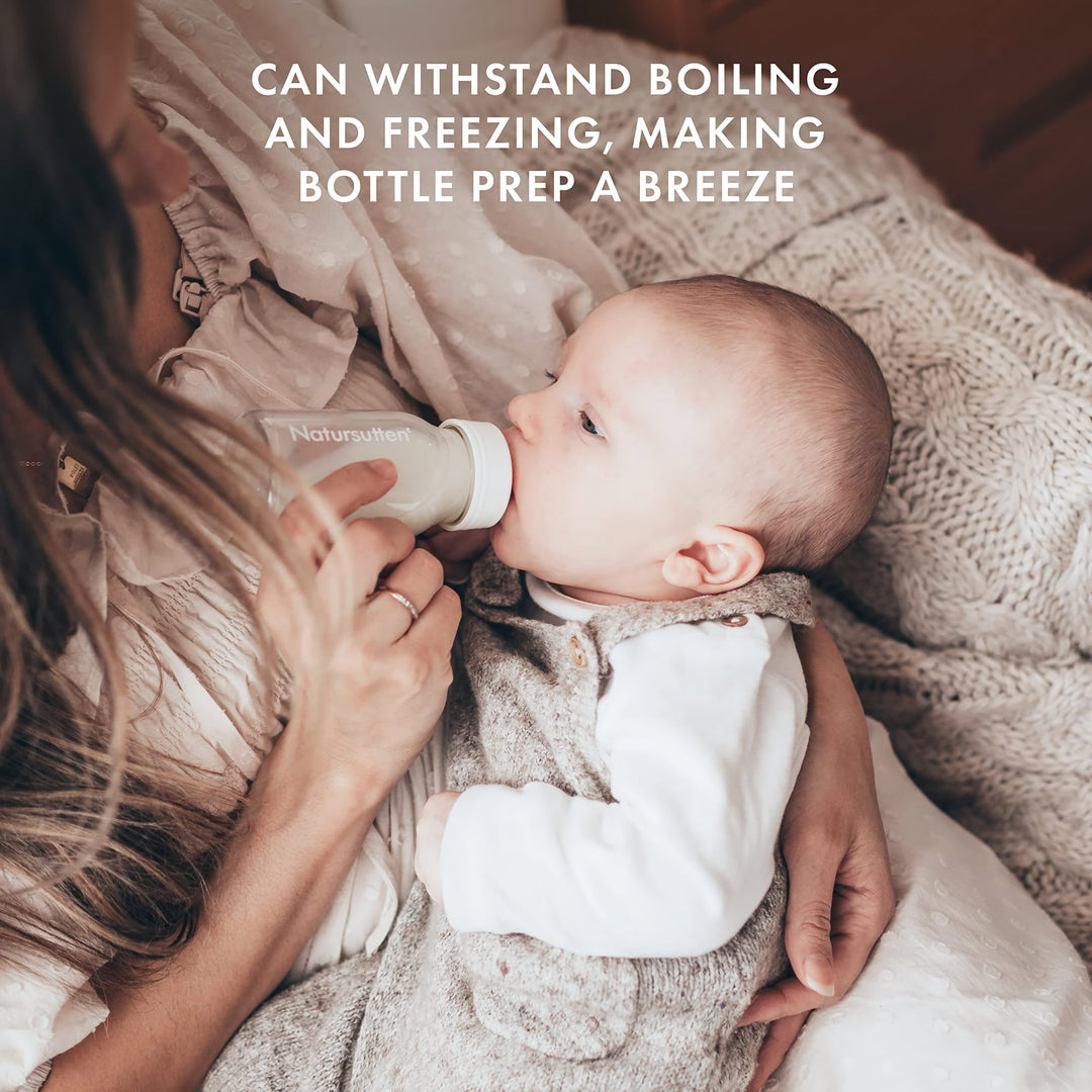 Baby drinking from Natursutten glass bottle held by mom, safe for boiling and freezing, ideal for convenient feeding prep