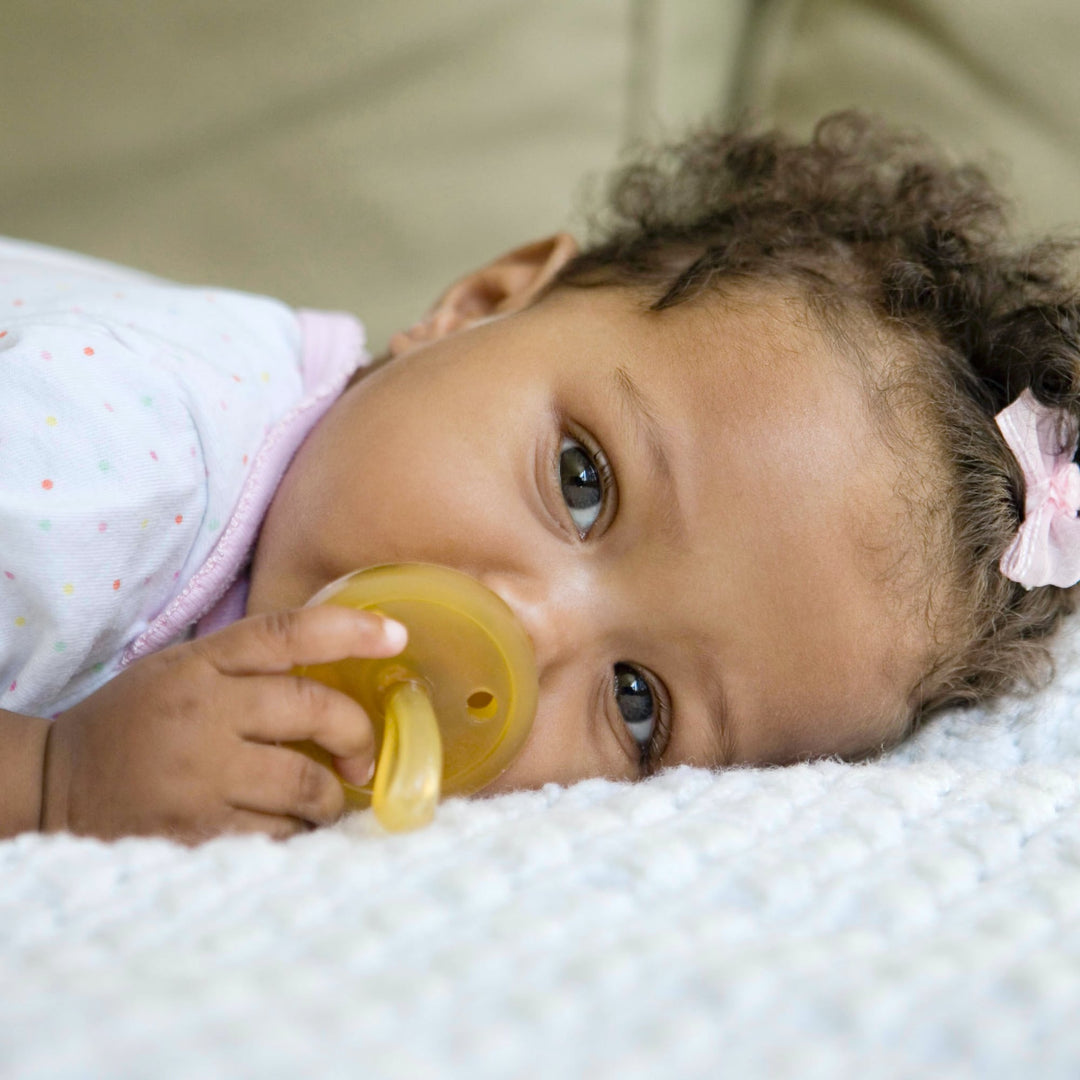 Baby lying down while soothing with Natursutten natural rubber pacifier