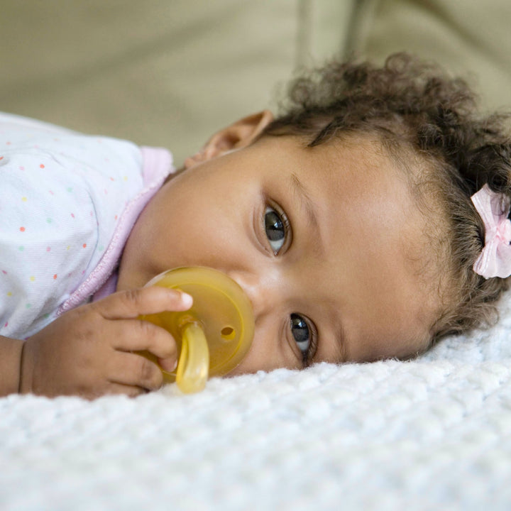 Baby lying down while soothing with Natursutten natural rubber pacifier