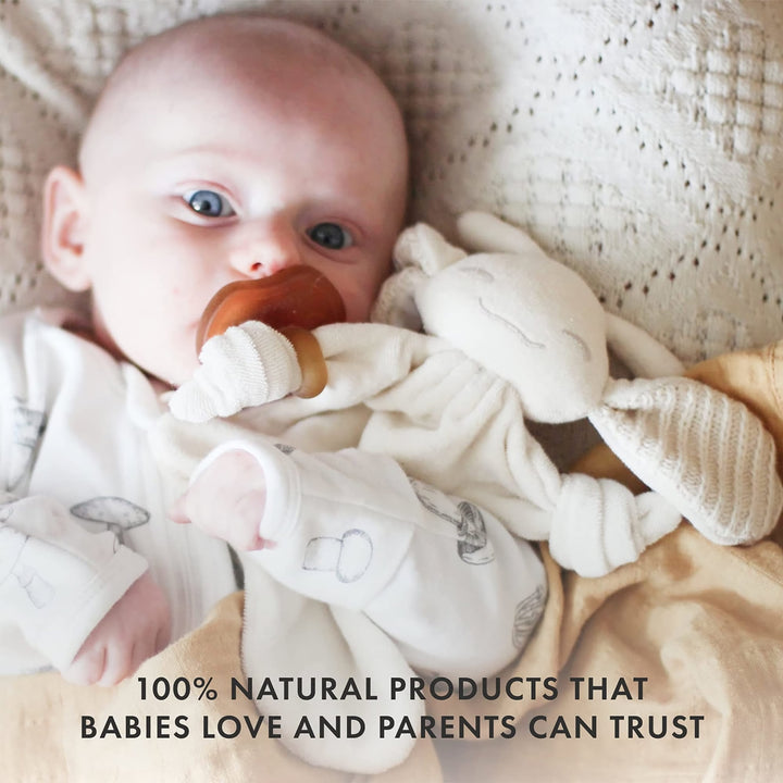 Baby holding Natursutten PaciPixy comforter with attached natural rubber pacifier, safe and trusted by parents