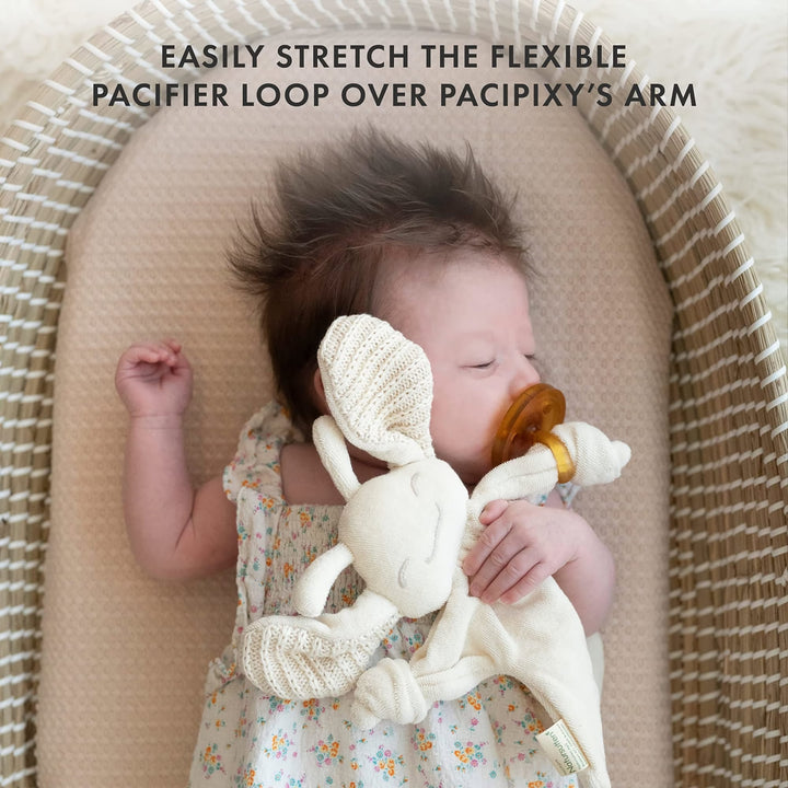 Baby sleeping with Natursutten PaciPixy comforter and pacifier looped over the arm, showing safe and flexible attachment