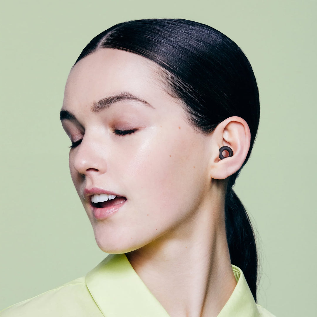 Model wearing Loop Quiet 2 earplugs in black, showing soft silicone design and comfortable in-ear fit