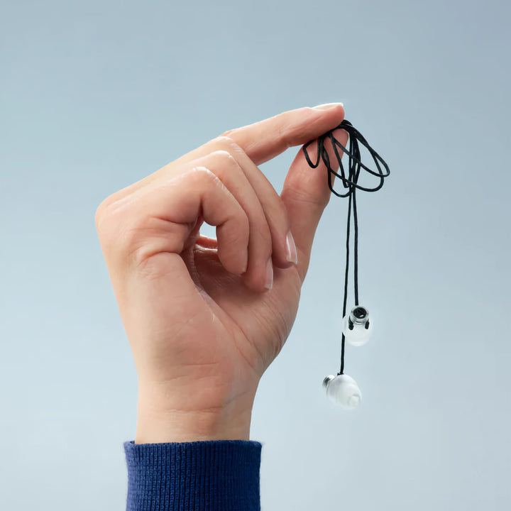 Hand holding Alpine Cord with earplugs attached for easy access and storage
