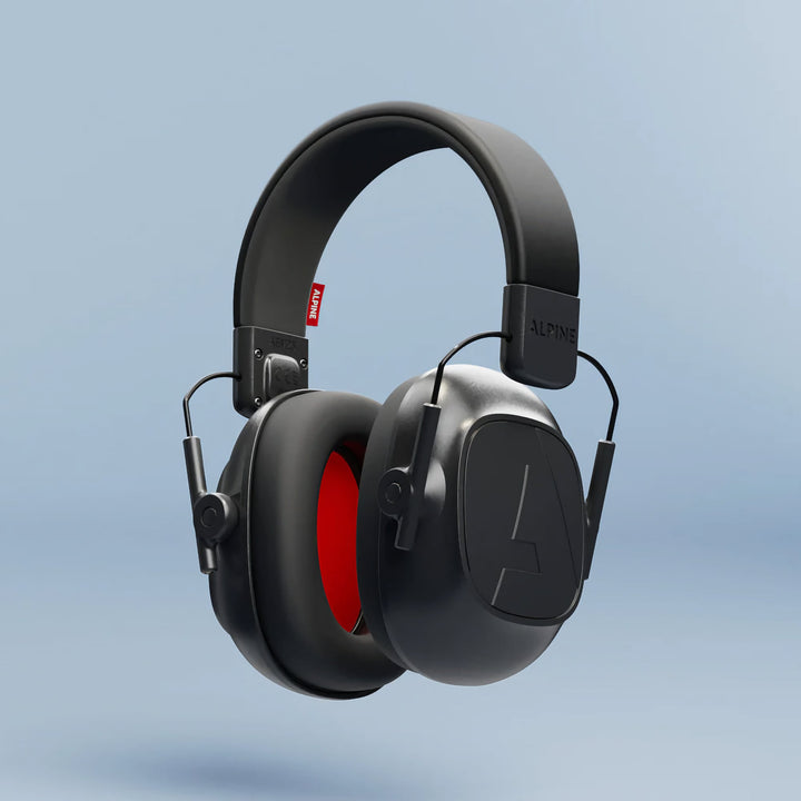 Alpine Defender Earmuffs in black with red interior shown in a floating close-up on a light blue background