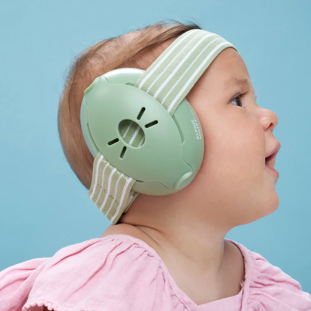 Side profile of baby wearing Alpine Muffy Baby Earmuffs in green, providing comfortable noise protection with a soft, adjustable headband.