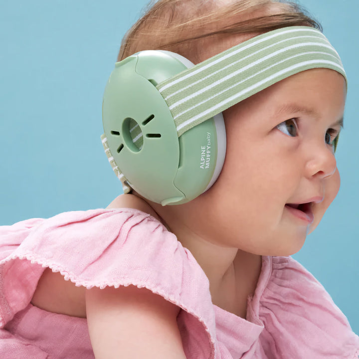 Baby wearing Alpine Muffy Baby Earmuffs in green, designed for comfortable noise protection with a soft, adjustable headband.