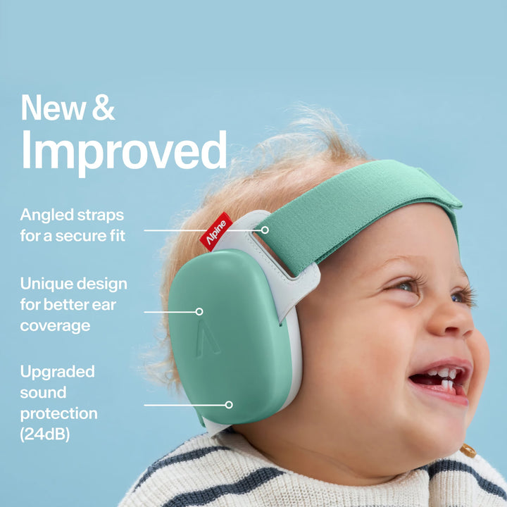 Smiling baby wearing Alpine Muffy Baby sage green earmuffs with angled straps, secure fit, and 24dB certified noise protection