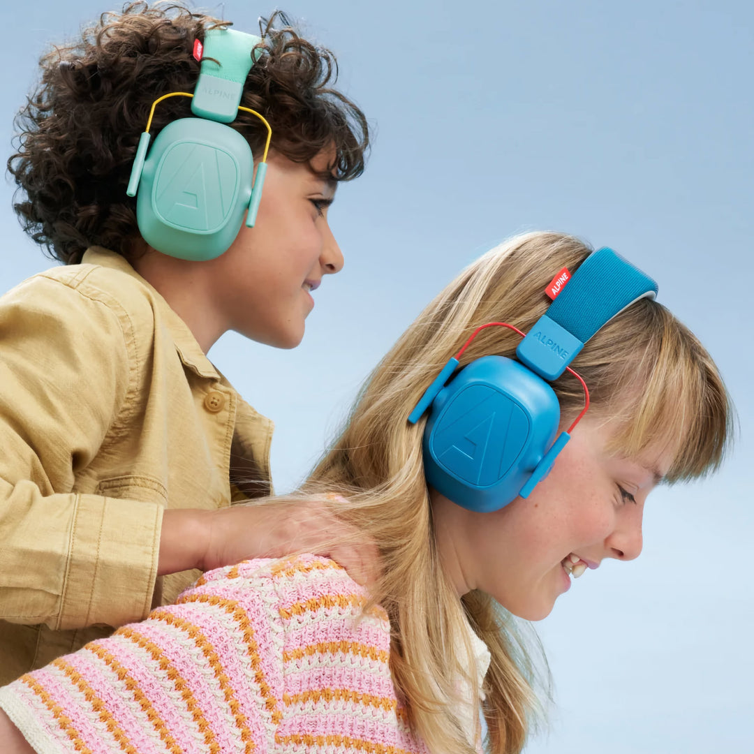 Two children wearing Alpine Muffy Kids Earmuffs in mint and blue, enjoying noise protection and comfort during play, ideal for kids aged 5–16.