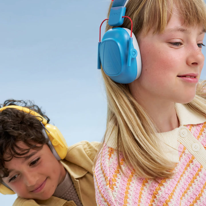 Two children wearing Alpine Muffy Kids Earmuffs in yellow and blue, demonstrating noise protection and comfort during play, ideal for kids aged 5–16.