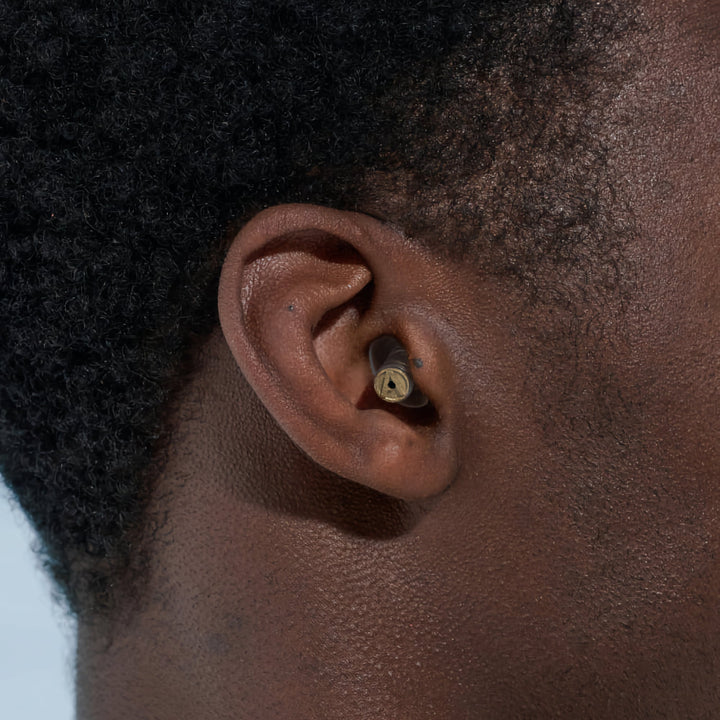 Alpine MusicSafe Pro earplugs with gold filter shown worn in ear, offering safe and clear sound protection for musicians