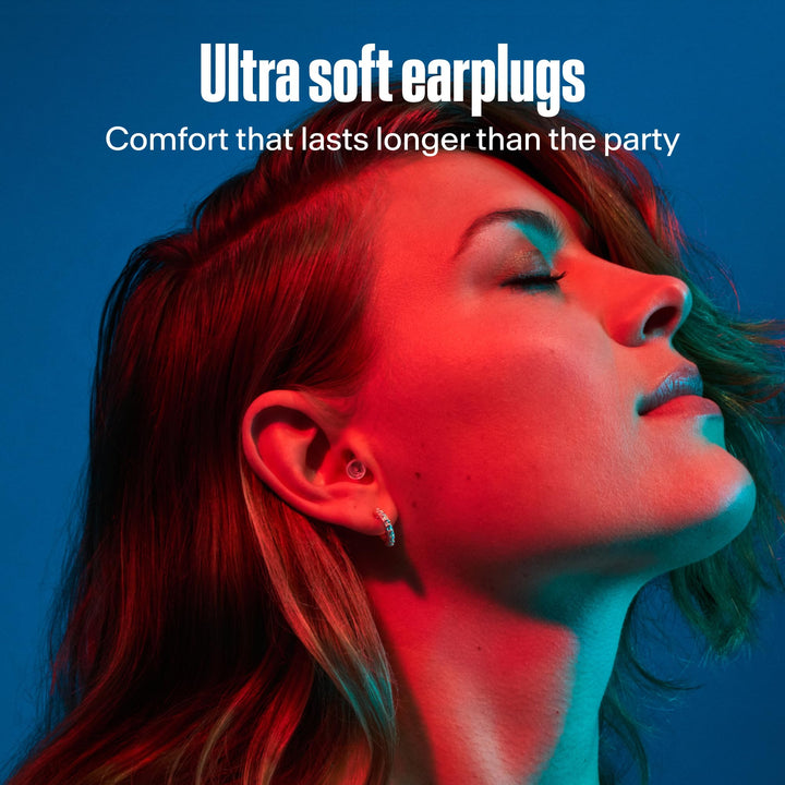 Woman wearing transparent Alpine PartyPlug earplugs in colored lighting, highlighting their soft, comfortable fit