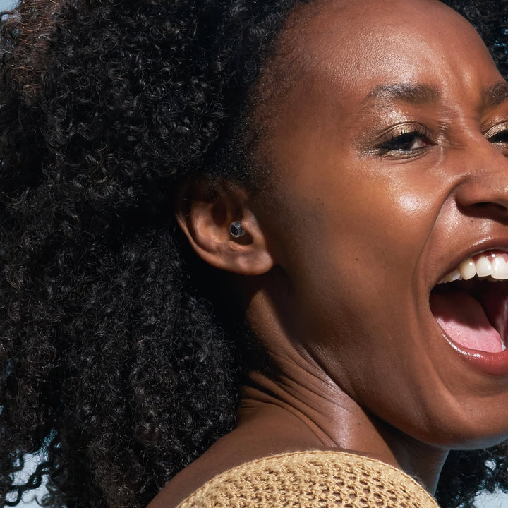 Woman wearing Alpine PartyPlug Pro Natural earplugs, designed for discreet hearing protection at concerts, festivals, and nightlife events.