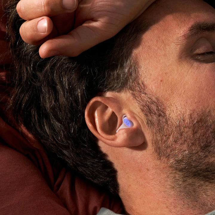 Man wearing Alpine SleepDeep earplugs while sleeping on his side, showcasing comfortable fit for side sleepers.