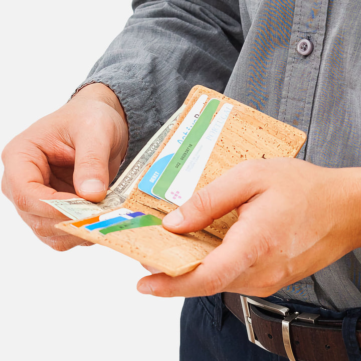 Man holding light brown Corkor Vegan Cork Slim Bifold Wallet with cards and cash inside, showcasing eco-friendly and minimalist design.