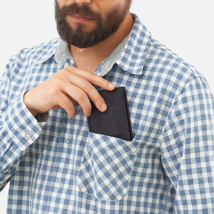 Man placing a Black Corkor Vegan Cork Wallet into his shirt pocket, showcasing its slim, pocket-friendly design.