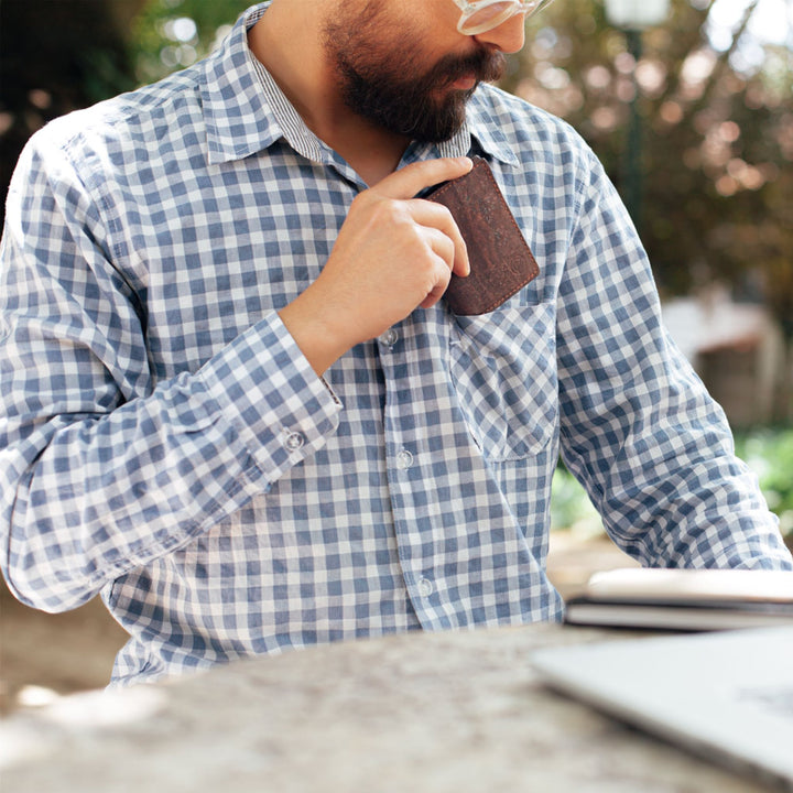 Man placing a dark brown Corkor Vegan Cork Wallet into his shirt pocket, emphasizing its slim and lightweight design.