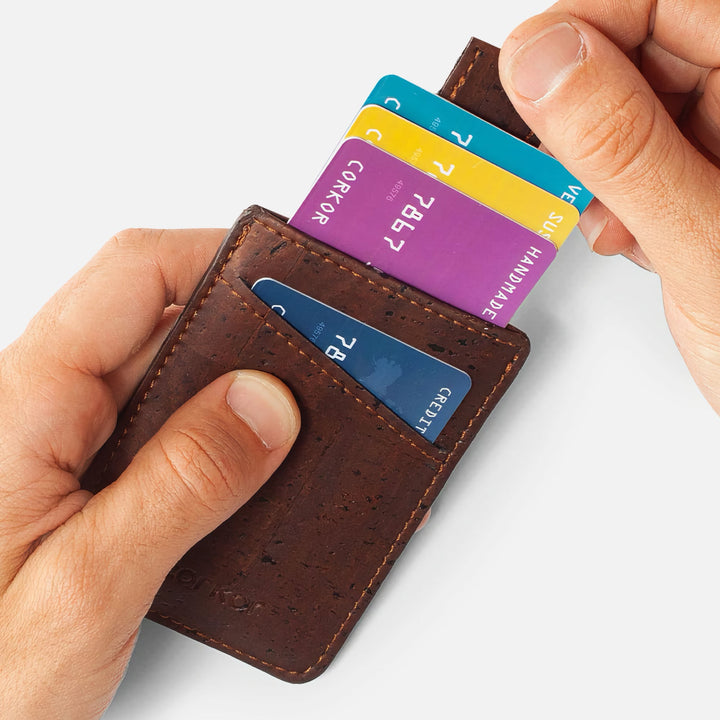 Hands using the pull-tab feature on the Corkor CK241 dark brown vegan cork card sleeve wallet, demonstrating easy access to stored cards in a compact, eco-friendly design.