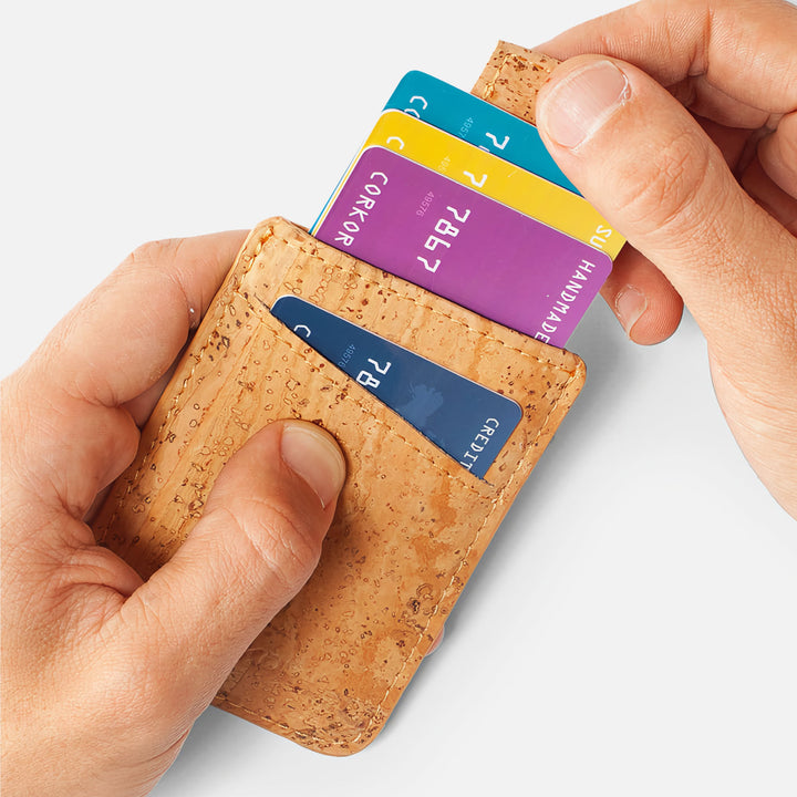 Hands using the pull-tab feature on the Corkor CK241 light brown vegan cork card sleeve wallet, demonstrating easy access to stored cards in a sustainable, minimalist design.