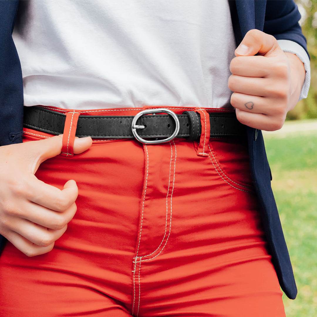 Close-up of a black Corkor vegan cork belt with a silver buckle, styled with red pants and a casual white top.