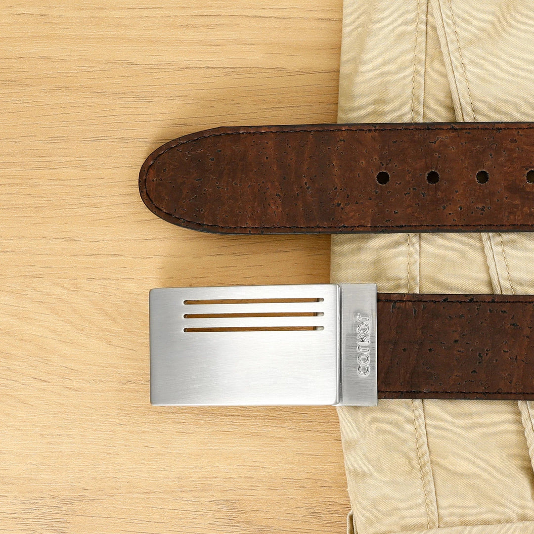 Corkor vegan men's reversible cork belt in brown with silver plaque buckle, flat lay styled with beige trousers