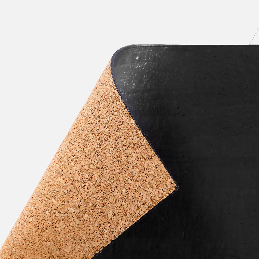 Close-up of Corkor black mouse pad with a lifted corner showing the cork-textured backing