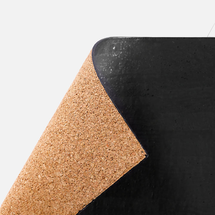 Close-up of Corkor black mouse pad with a lifted corner showing the cork-textured backing