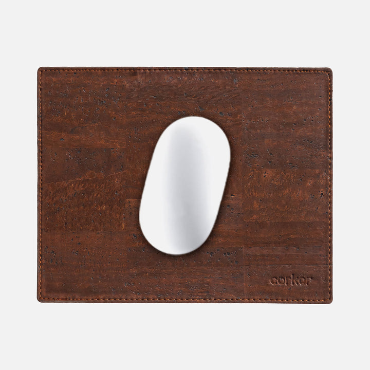 Corkor dark brown mouse pad with stitched edges and embossed logo, shown from above with a white mouse