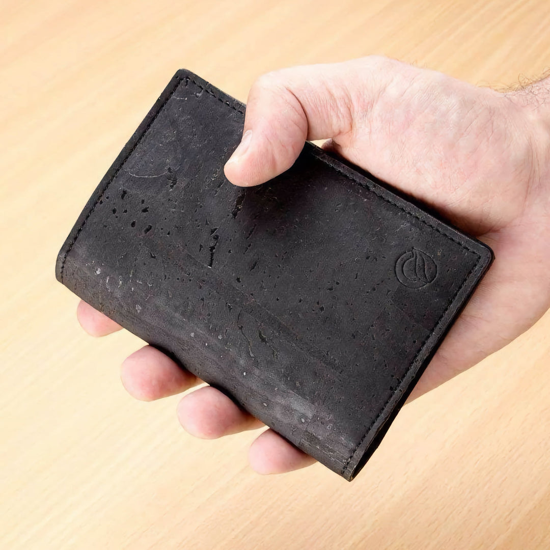 Corkor Vegan Cork Passport Wallet in black, shown handheld highlighting slim design and natural cork texture