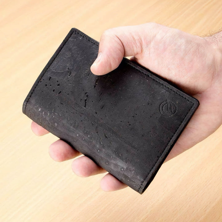 Corkor Vegan Cork Passport Wallet in black, shown handheld highlighting slim design and natural cork texture