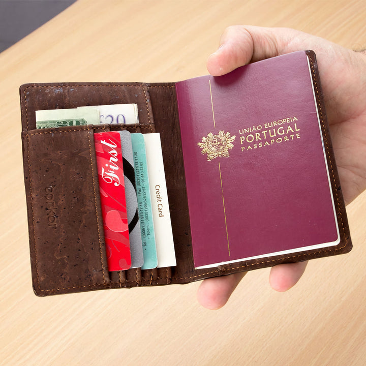 Corkor Vegan Cork Passport Wallet in Dark Brown, shown in use holding passport, cards, and cash in hand