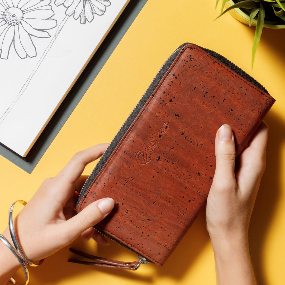 Hands holding Corkor Vegan Cork Women's Long Wallet in red, emphasizing its natural cork texture and stylish appearance.