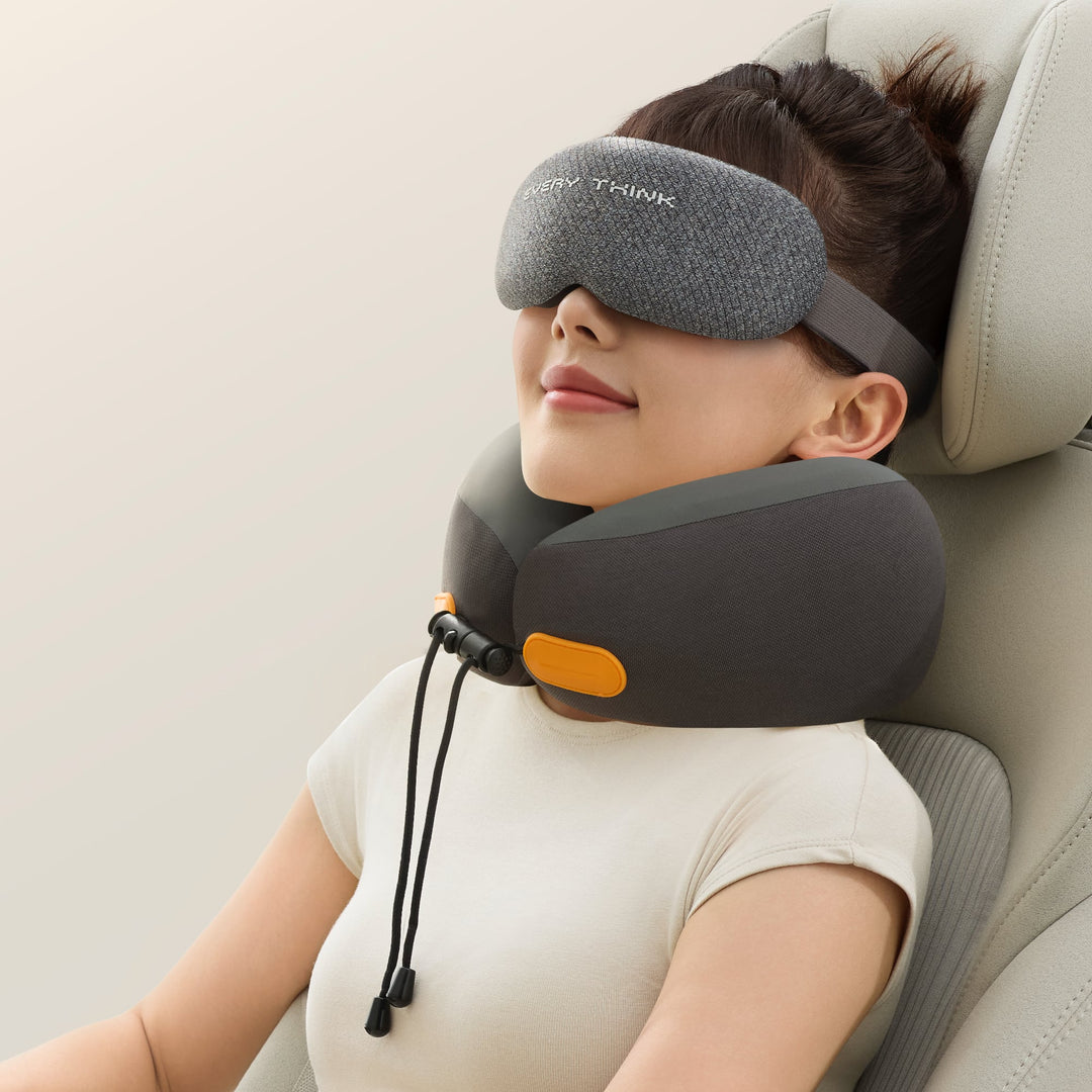 Woman using the EVERYTHINK ES2 black travel neck pillow and matching sleep mask while resting in a car seat