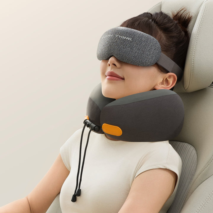 Woman using the EVERYTHINK ES2 black travel neck pillow and matching sleep mask while resting in a car seat