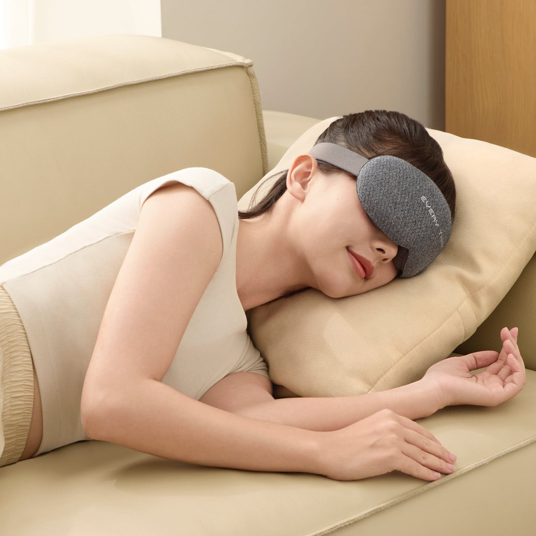 Woman resting on couch wearing EVERYTHINK VE2 3D Blackout Sleep Mask in gray, demonstrating comfort and full light blocking