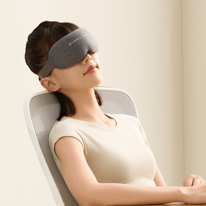 EVERYTHINK VE2 3D Blackout Sleep Mask in gray worn by a woman resting comfortably on a chair, ideal for home or office naps