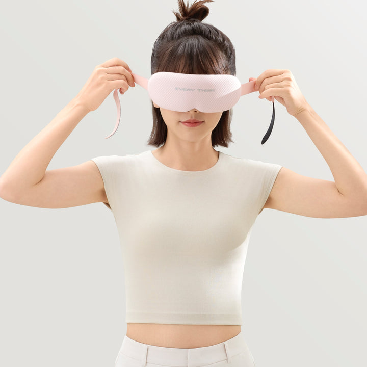 Woman adjusting strap of EVERYTHINK VE2 3D Blackout Sleep Mask in pink, showing flexible fit and comfort