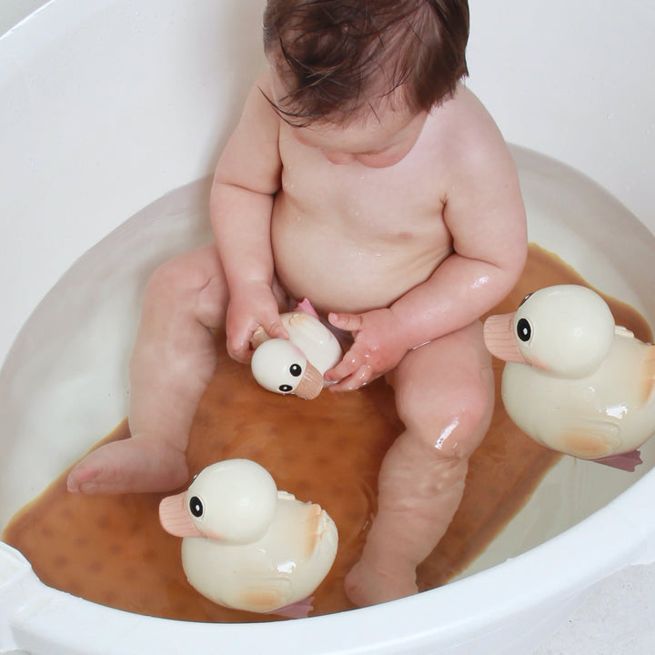 Baby playing with HEVEA Kawan Rubber Ducks in a bathtub, showcasing their natural, safe, and mold-free design for bath time fun.