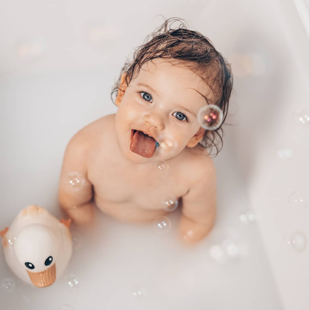 Baby playing in bathtub with Hevea Kawan Rubber Duck Original natural rubber bath toy, eco-friendly mold-free design