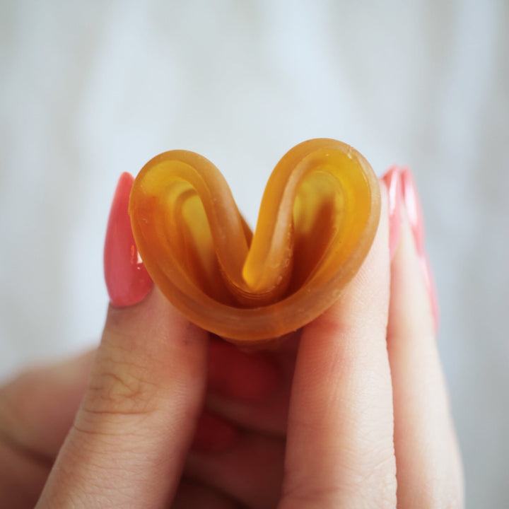 Hevea Loop Menstrual Cup in natural rubber color showing folding technique for easy insertion.