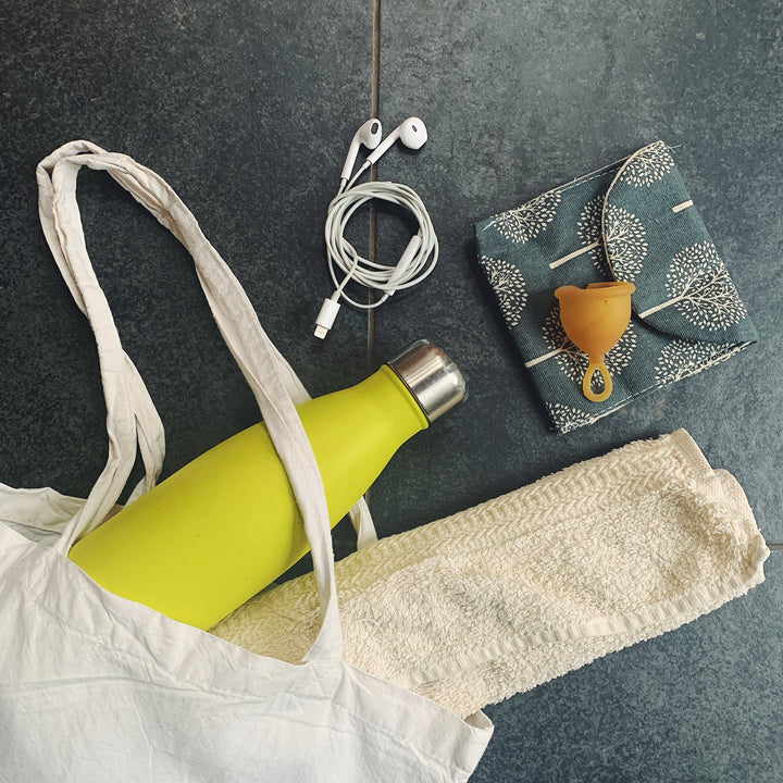 Hevea Loop Menstrual Cup in natural rubber color with travel essentials, including upcycled cotton storage bag.