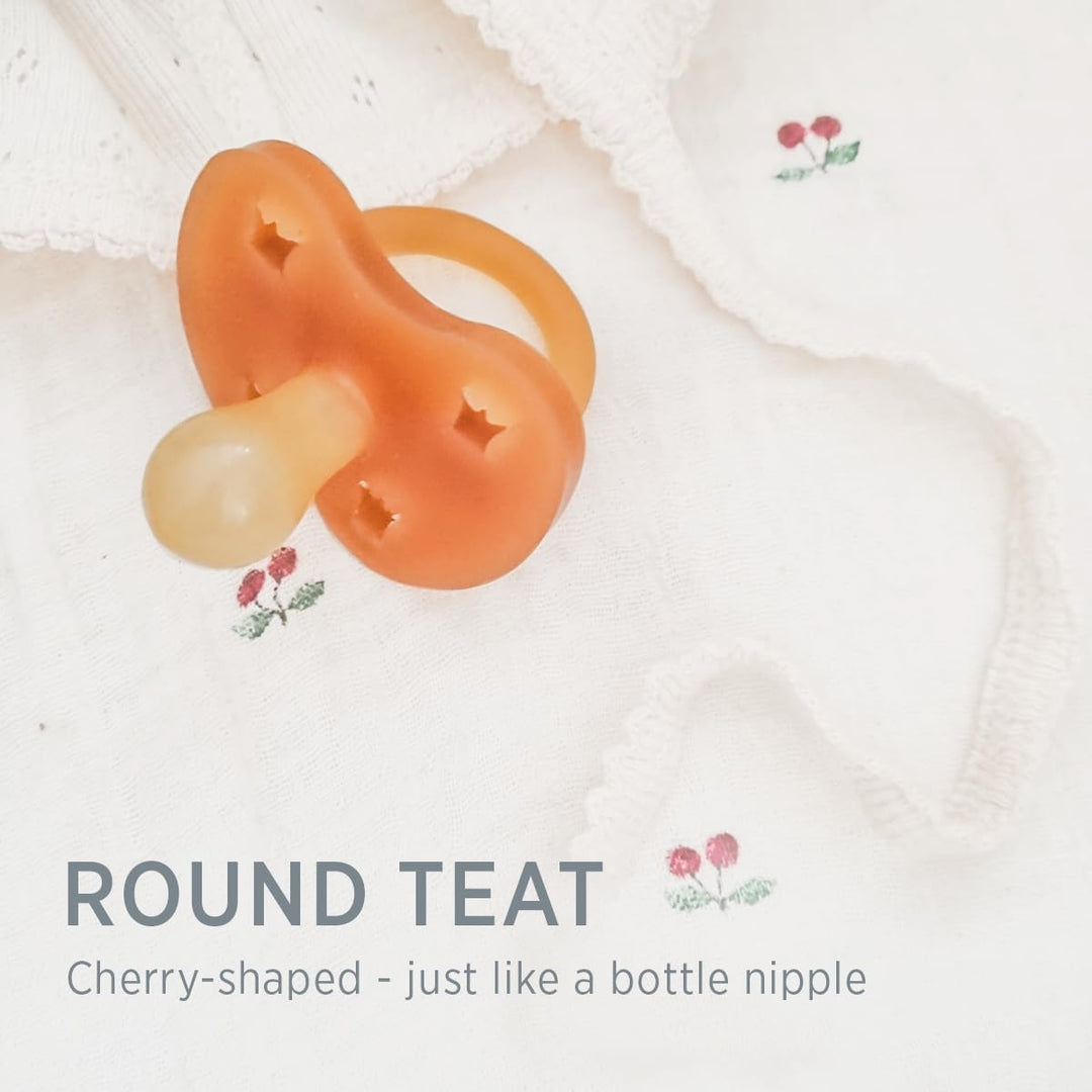 Hevea natural rubber pacifier with round cherry-shaped teat on soft baby fabric