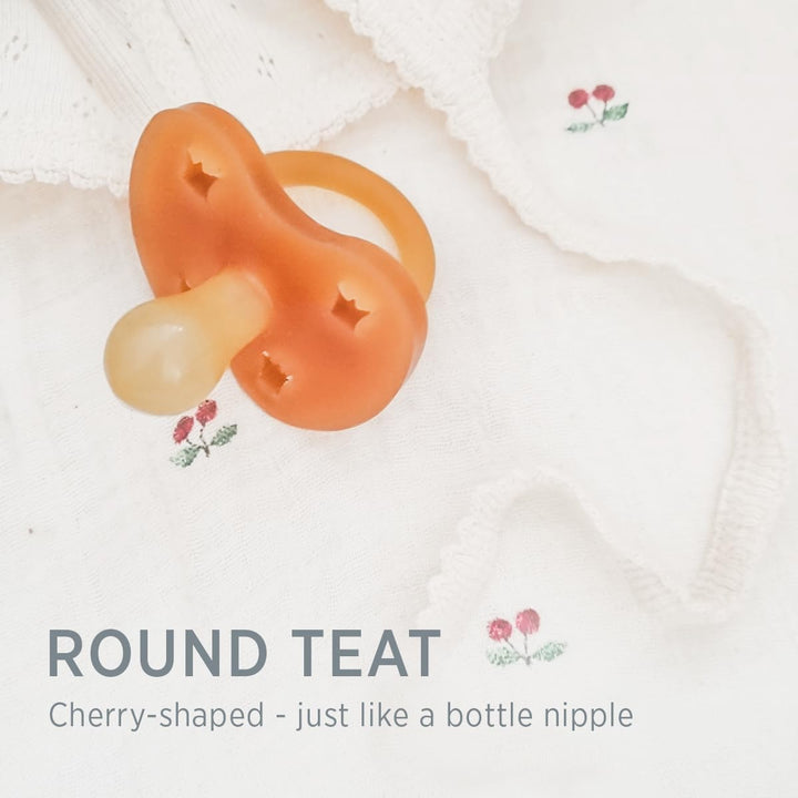 Hevea natural rubber pacifier with round cherry-shaped teat on soft baby fabric