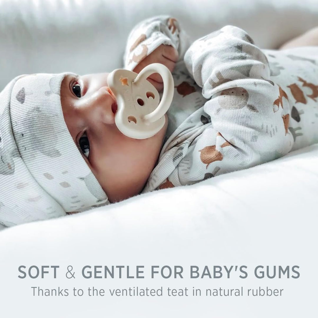 Baby using a milky white Hevea natural rubber pacifier with ventilated teat