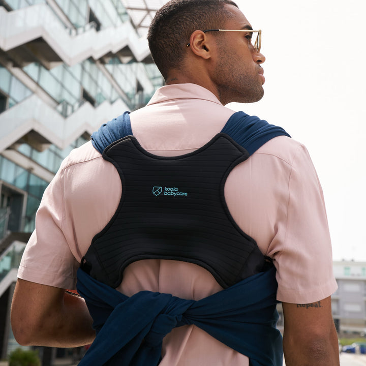Back view of dad wearing Koala Cuddle Band 2 in dark blue, showing ergonomic padded support while walking outdoors