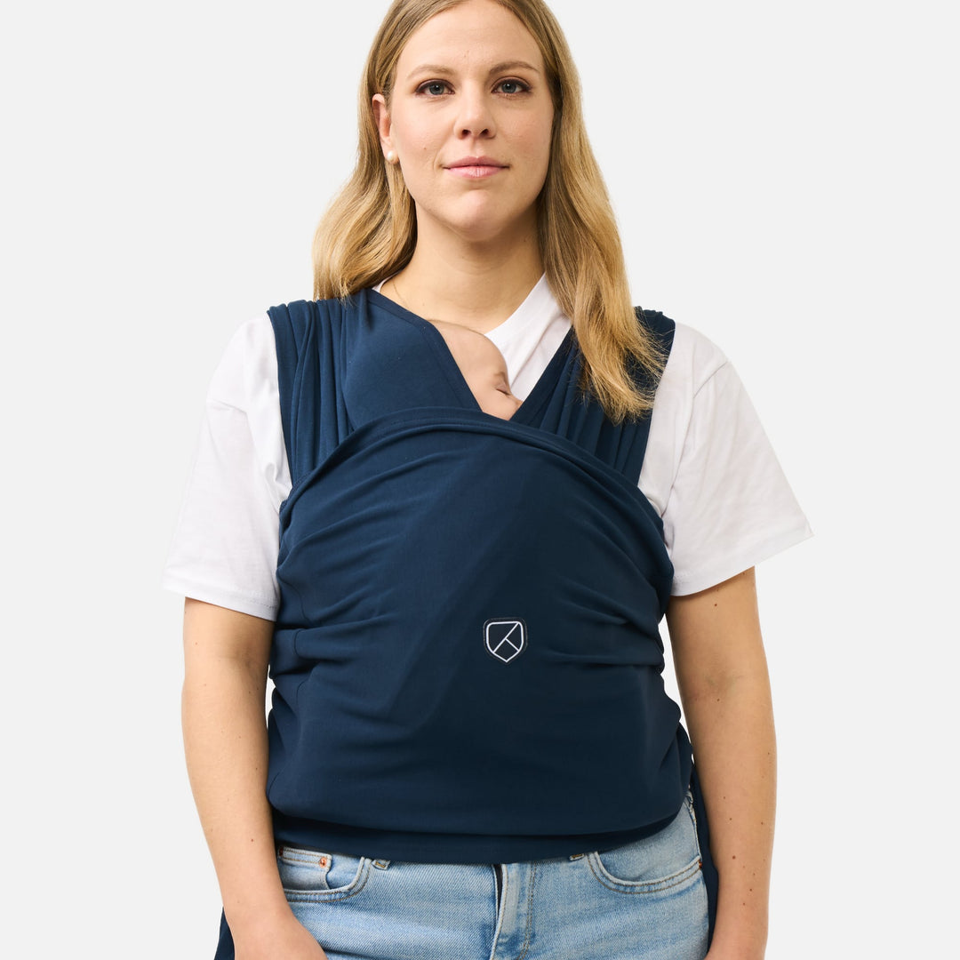 Woman wearing Koala Babycare Koala Cuddle Band 2 in dark blue with baby resting securely in front wrap carrier